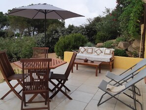 A patio with a table and chairs, a sofa, and an umbrella. - Appart , Belles Prestations Avec Terrasse vue mer Dans Villa (.CALCATOGGIO)