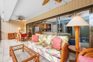 Uma sala de estar espaçosa com sofá, cadeiras, mesa de jantar e ventoinha no teto.
