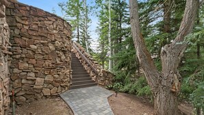 Una escalera de piedra que sube hacia un edificio, rodeado de árboles.