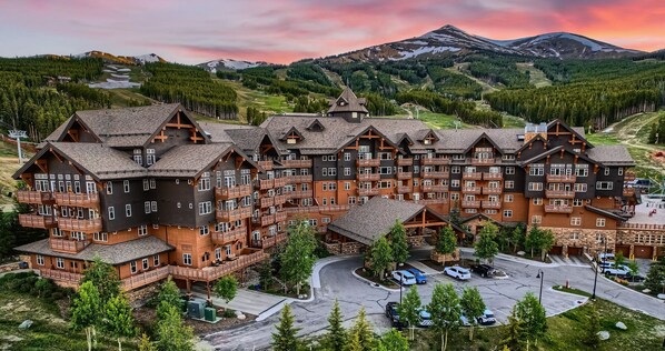A multi-story lodge with a ski slope in the background.