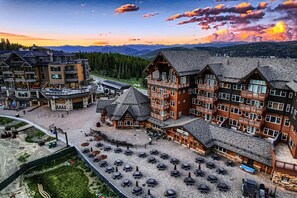 Ein Hotel mit mehreren Gebäuden, Außenbestuhlung und einer Bergkulisse.