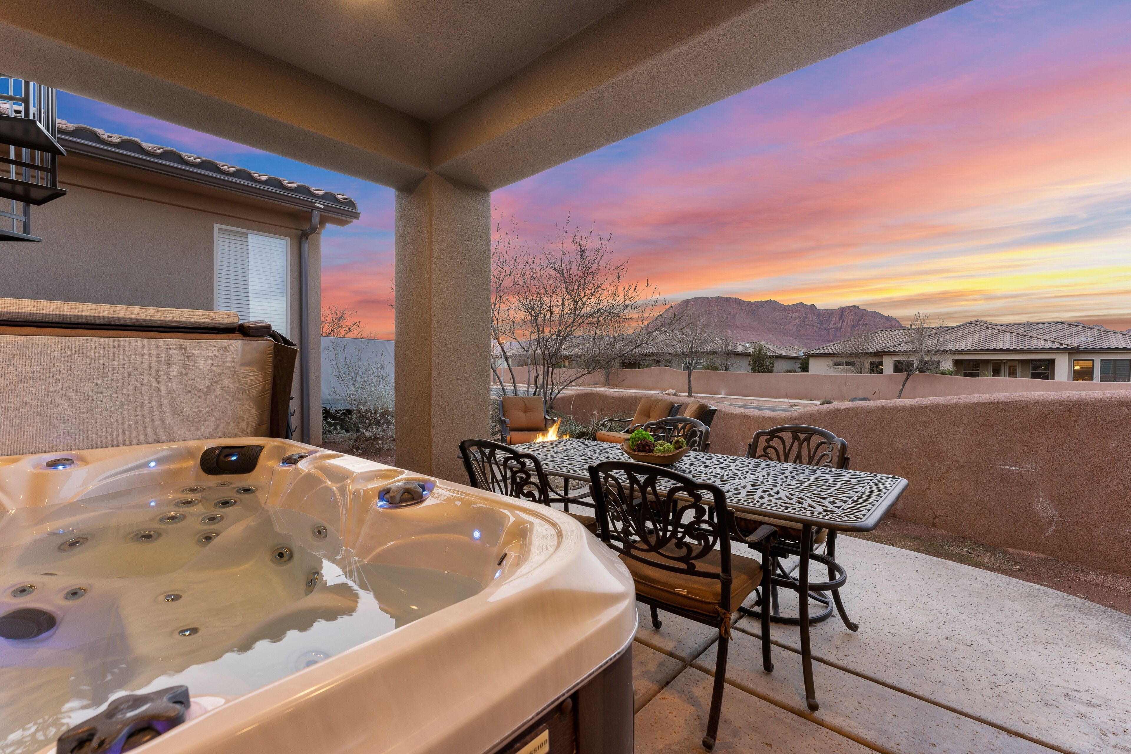 A hot tub and outdoor seating area with a view of mountains during sunset.