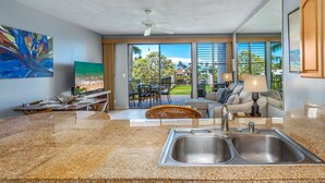 A modern kitchen with a granite countertop, stainless steel sink, and a dining area with a table and chairs.