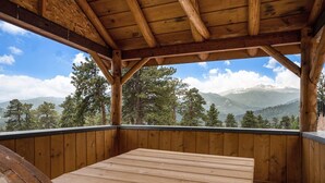 A wooden deck with a bench and a view of mountains and trees.
