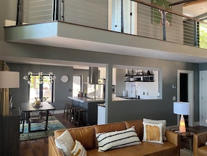 A spacious living area with a brown leather sofa, a dining table, and a kitchen in the background. - Unique home and 3 level bunkhouse.  Lake of the Ozarks. Accommodate 24 guests!   (Gravois Mills)