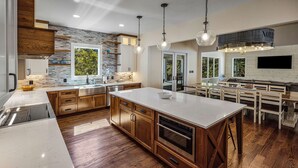 A modern kitchen with a large island, wooden cabinets, and a stone backsplash.