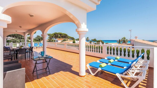 A terrace with sun loungers, a table, and chairs, overlooking a coastal view. - Binifortu - Four Bedroom Villa, Sleeps 8 (Punta Prima)