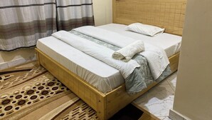 A single bed with a wooden frame, a headboard, and a patterned rug. - Virunga House (Muhoza)