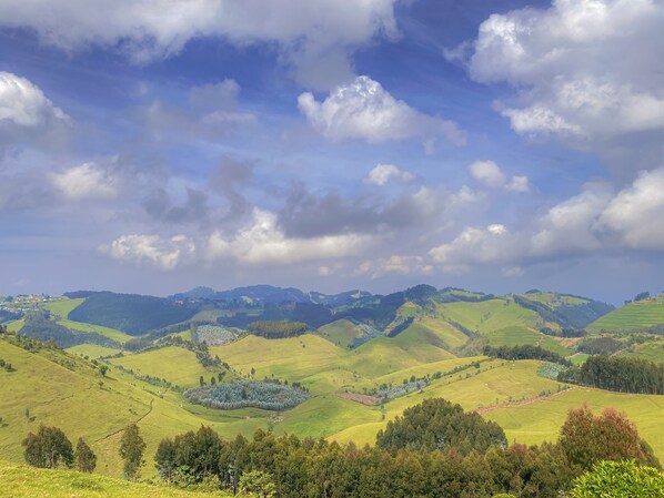 Rolling green hills with a clear sky and scattered clouds.