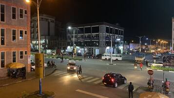 A nighttime urban street scene with buildings, vehicles, and pedestrians.