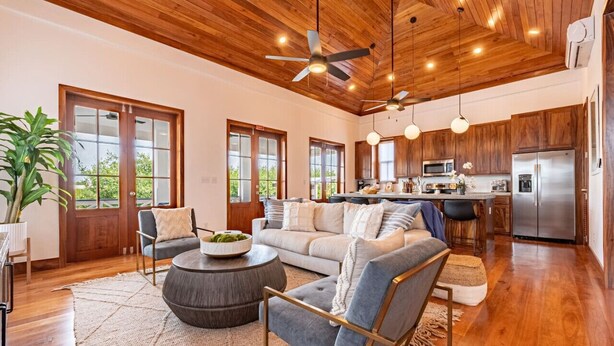 A spacious living area with a wooden ceiling, large windows, a kitchen with modern appliances, and a cozy seating arrangement. - The Weekender & Mistico Beach Club + Boat Shuttle (San Pedro)