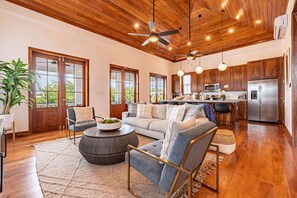 A spacious living area with a wooden ceiling, large windows, a kitchen with modern appliances, and a cozy seating arrangement. - The Weekender & Mistico Beach Club + Boat Shuttle (San Pedro)