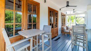 A covered outdoor seating area with wooden tables and chairs, large windows, and ceiling fans. - The Weekender & Mistico Beach Club + Boat Shuttle (San Pedro)
