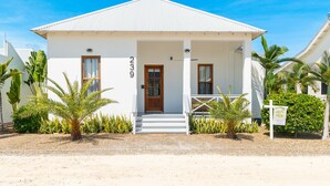 A white building with a number '239' on the side, a wooden door, and a porch with steps. - The Weekender & Mistico Beach Club + Boat Shuttle (San Pedro)