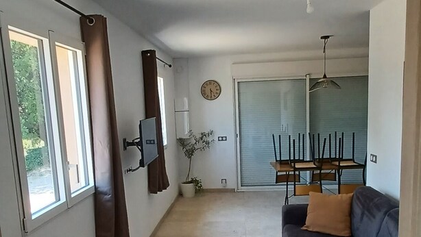 A spacious living area with a sofa, a wooden table, and a dining table with chairs.
