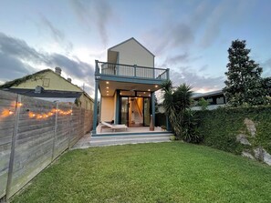 Una casa a due piani con un balcone, una porta d'ingresso e una scalinata che conduce all'entrata.