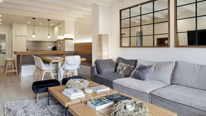 A modern living room with a grey sofa, a wooden coffee table, and a kitchen in the background. - Port Luxe by FeelFree Rentals (Baqueira)