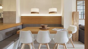 A modern dining area with a wooden table, white chairs, and pendant lights. - Port Luxe by FeelFree Rentals (Baqueira)