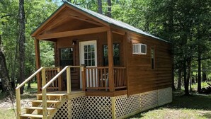 Uma cabana de madeira com varanda, escadas e um deck cercado.