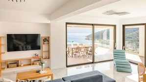 A modern living room with a large flat-screen TV, wooden shelves, a coffee table, and a sofa.