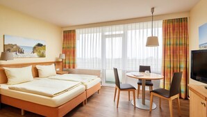 Een hotelkamer met een bed, een bureau, een stoel, een televisie en een raam met gordijnen.
