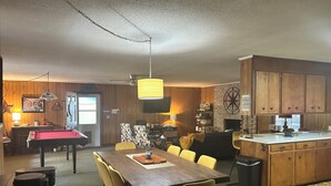 Ein Essbereich mit Billardtisch, eine Küche mit Holzausstattung und ein Kamin.