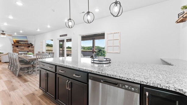 A modern kitchen with granite countertops, stainless steel appliances, and pendant lighting.