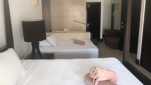 A hotel room with two beds, a bathroom, and a seating area.