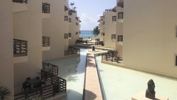 A resort with a central pool, multiple balconies, and a view of the ocean.