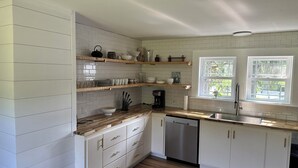 A kitchen with white cabinetry, wooden countertops, and a dishwasher. There are two windows providing natural light. - ANY BIG PARTY!!!! (Standish)