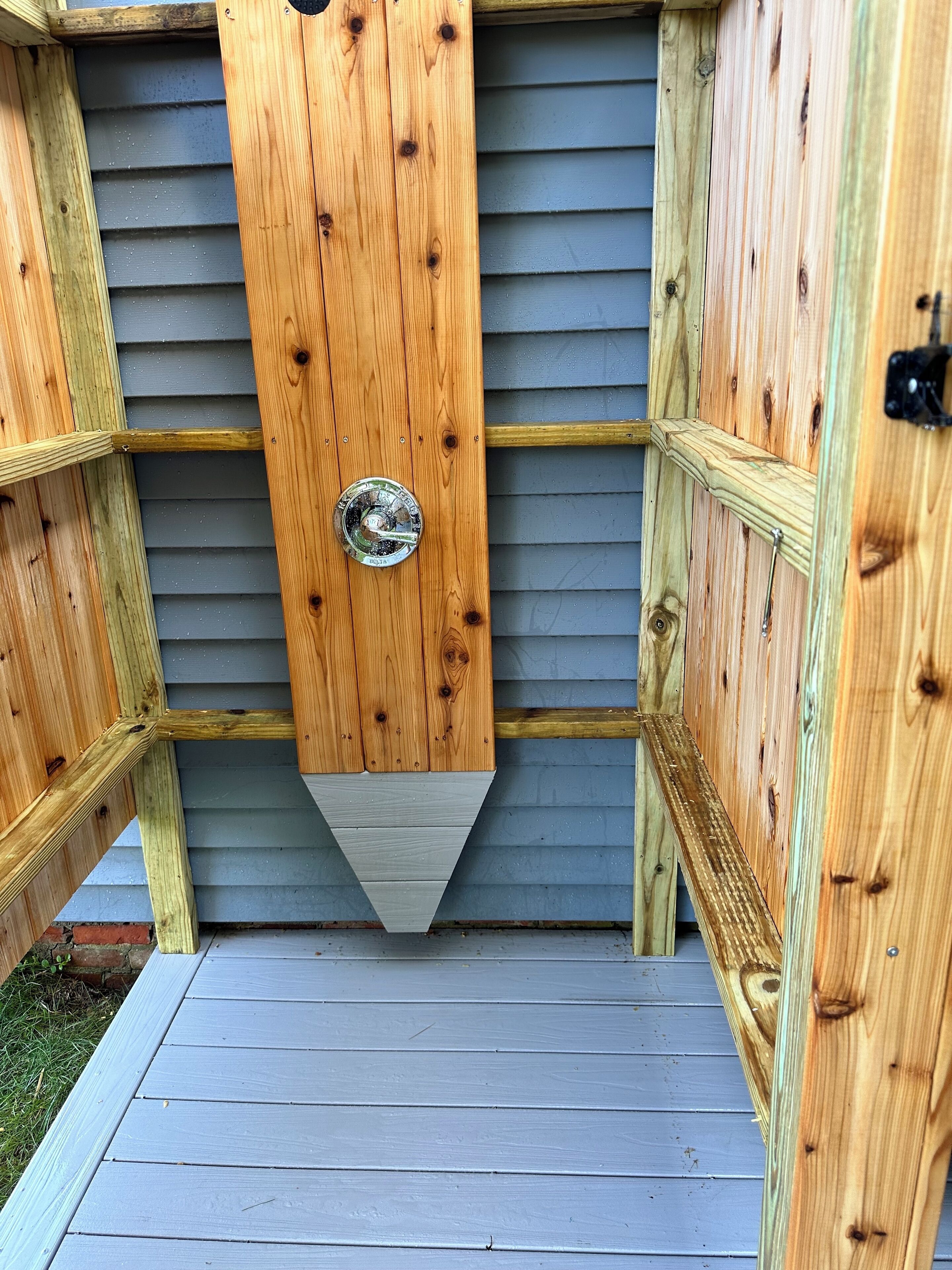 Une structure en bois dotée d’une porte en métal et d’un toit en pente.