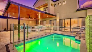 Una casa moderna con piscina, terraza techada y zona de estar al aire libre.
