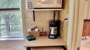 A kitchenette with a microwave, coffee maker, and a small refrigerator.