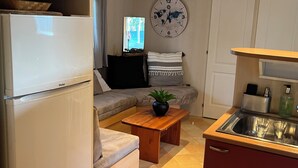 A compact living space with a kitchenette, a sofa, a small dining table, and a clock on the wall. - Mobil Home 4/6 Clim Terrasse Barbecue Piscines Toboggan Animations (Le Muy)