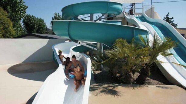A water park with multiple slides and a sandy area with palm trees. - Mobil Home 4/6 Clim Terrasse Barbecue Piscines Toboggan Animations (Le Muy)