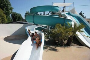 A water park with multiple slides and a sandy area with palm trees. - Mobil Home 4/6 Clim Terrasse Barbecue Piscines Toboggan Animations (Le Muy)