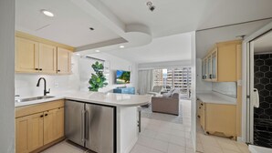 Een moderne keuken met inbouwapparatuur, een zithoek met een bank en uitzicht op hoge gebouwen.