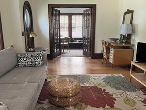 A living room with a sofa, a coffee table, a TV stand, and a dining area with a table and chairs. - 1920 Craftsman Style Home. Walking Distance to Paine Art Center and Gardens. (Oshkosh)
