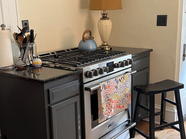 Une cuisine équipée d’une cuisinière, d’un four et d’un petit tabouret.