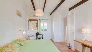 Une chambre à coucher avec un lit, une chaise, une table, un miroir et une fenêtre.