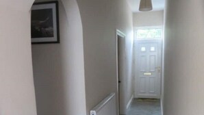 A hallway with a herringbone floor, white walls, and a door at the end. - 2 Railway Terrace (Hurworth Place)