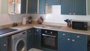 A compact kitchen with teal cabinets, a washing machine, a microwave, and a sink. - 2 Railway Terrace (Hurworth Place)
