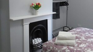 A bedroom with a bed, a fireplace, a painting of a bull, and a flower vase. - 2 Railway Terrace (Hurworth Place)