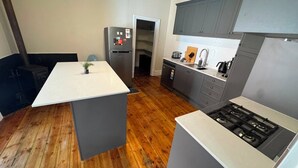 A modern kitchen with a central island, grey cabinetry, and a stainless steel refrigerator.