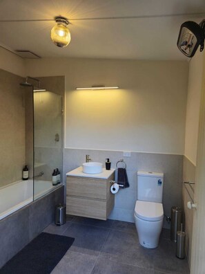 A modern bathroom with a bathtub, toilet, and sink.