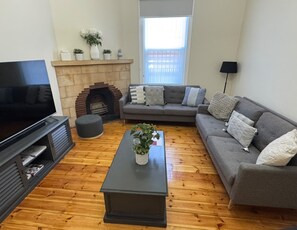 A living room with a fireplace, a sofa, a coffee table, and a television.