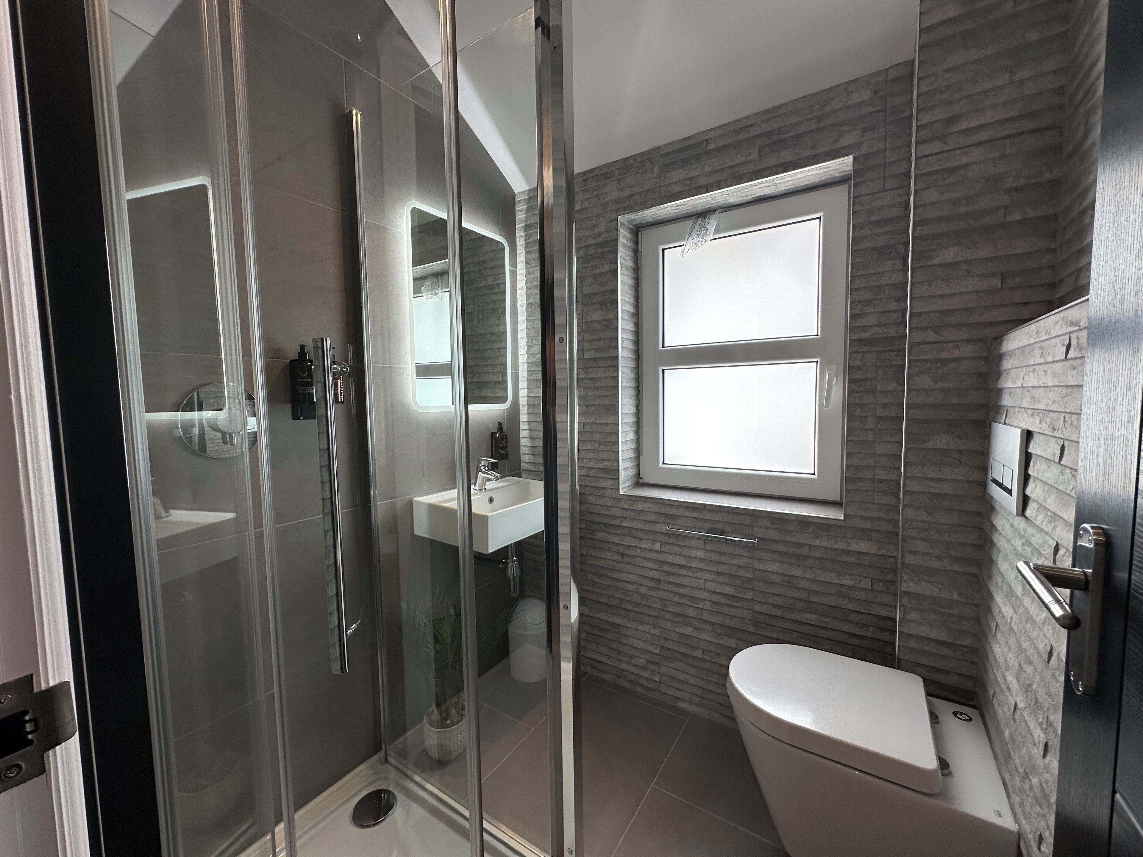 Een moderne badkamer met een douchecabine van glas, een wastafel en een toilet.