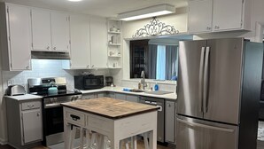 A modern kitchen with white cabinets, stainless steel appliances, and a wooden island.