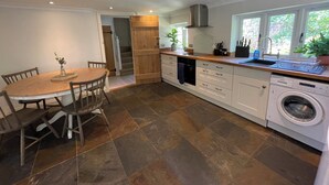 A modern kitchen with a dining area, built-in appliances, and a view of the outdoors. - Cottage with beautiful garden, 7 mins from Henley-on-Thames (Binfield Heath)