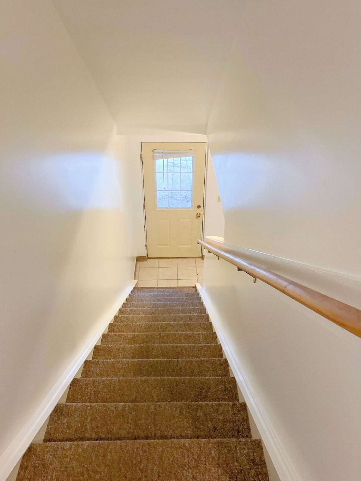 Un escalier avec une rampe menant à une porte dotée d’une fenêtre.